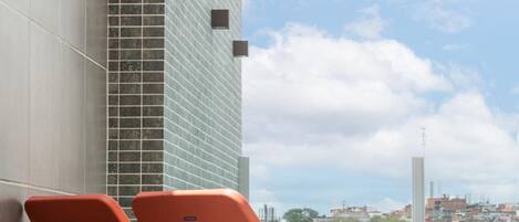 A modern building with a glass facade and a view of a cityscape in the background.