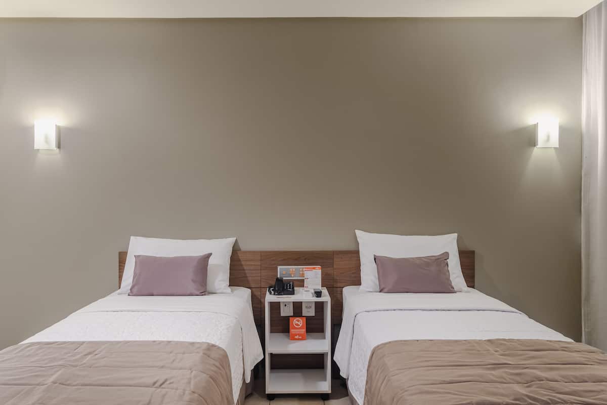 Hotelkamer met twee bedden, een nachtkastje, een telefoon, een koffiezetapparaat en een bordje met een rookverbod.