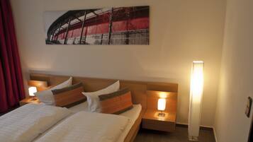 A hotel room with a bed, two bedside tables with lamps, a wall-mounted artwork, and a red curtain.