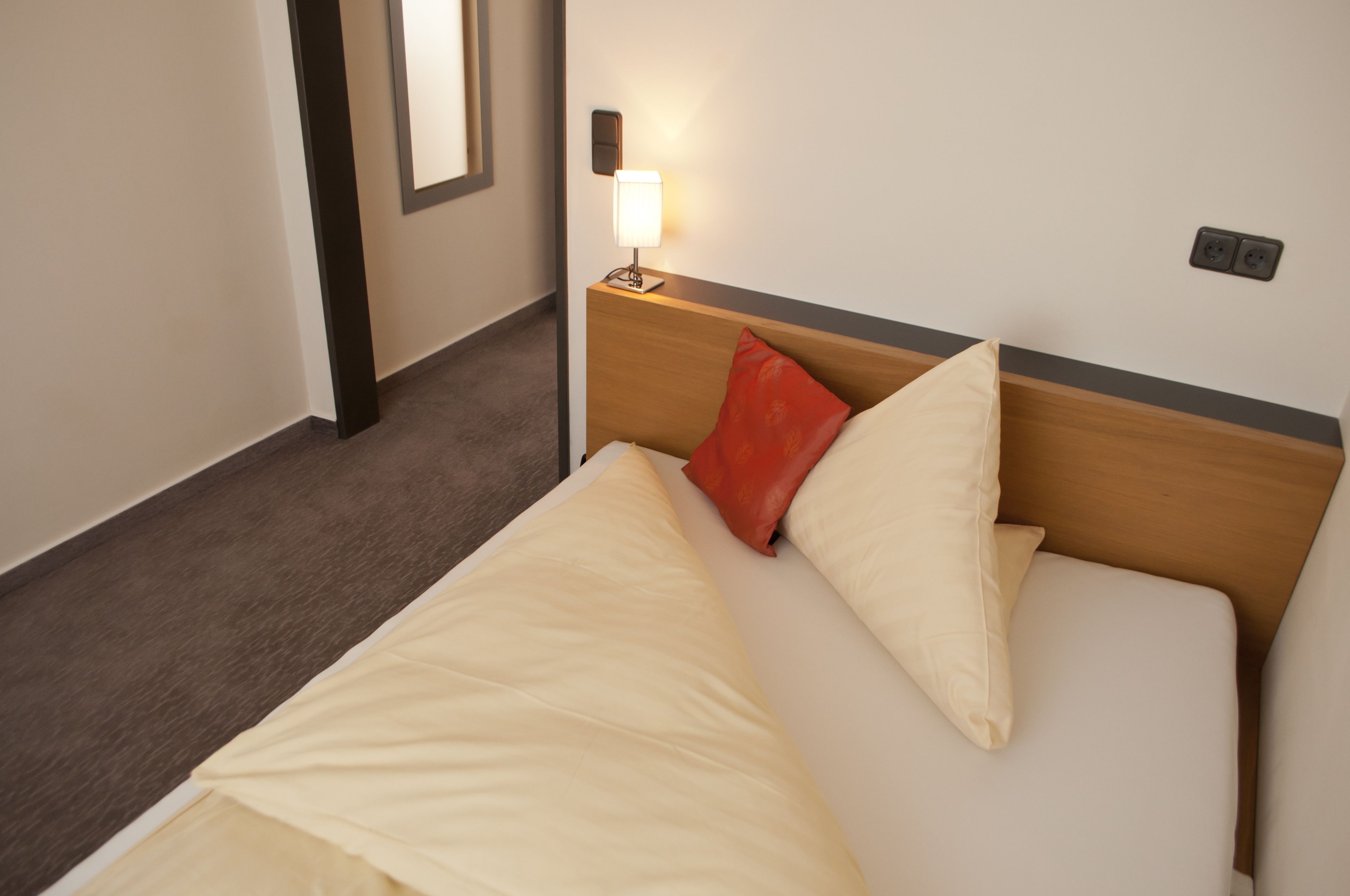 Ein Hotelzimmer mit einem Bett, einem Nachttisch mit Lampe und einer Steckdose.