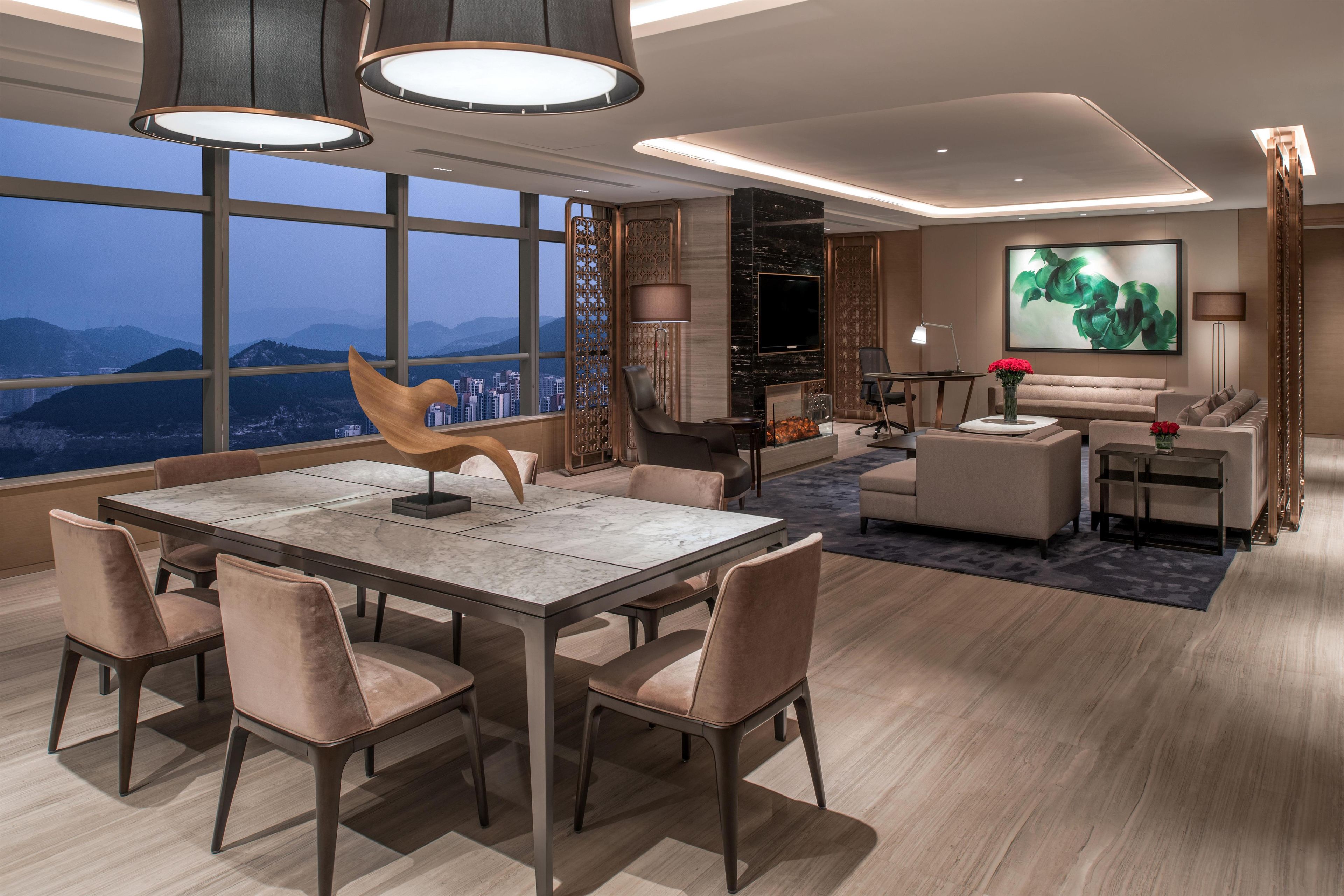 Ein modernes Interieur mit Essbereich, Sitzgelegenheiten und einem großen Fenster mit Blick auf die Stadt.