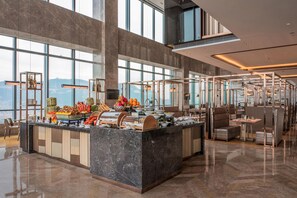 Un hall d’hôtel moderne avec un comptoir d’accueil en marbre, des espaces de détente et de grandes fenêtres offrant une vue sur la ville.