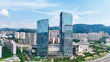 Two high-rise buildings with a modern glass facade, surrounded by a dense urban area with other residential and commercial buildings.