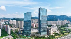 Two high-rise buildings with a modern glass facade, surrounded by a dense urban area with other residential and commercial buildings. - Hilton Jinan South Hotel & Residences (Jinan)