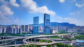 A cityscape with modern skyscrapers, a complex highway interchange, and a mountainous backdrop. - Hilton Jinan South Hotel & Residences (Jinan)