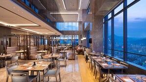 A modern restaurant with high ceilings, large windows, and a city view. - Hilton Jinan South Hotel & Residences (Jinan)