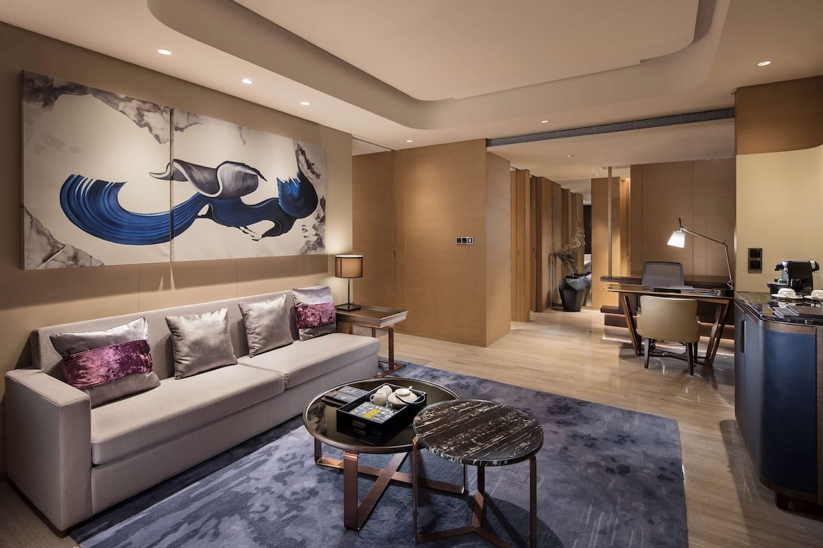 A modern living room with a sofa, coffee table, and a large abstract painting on the wall.