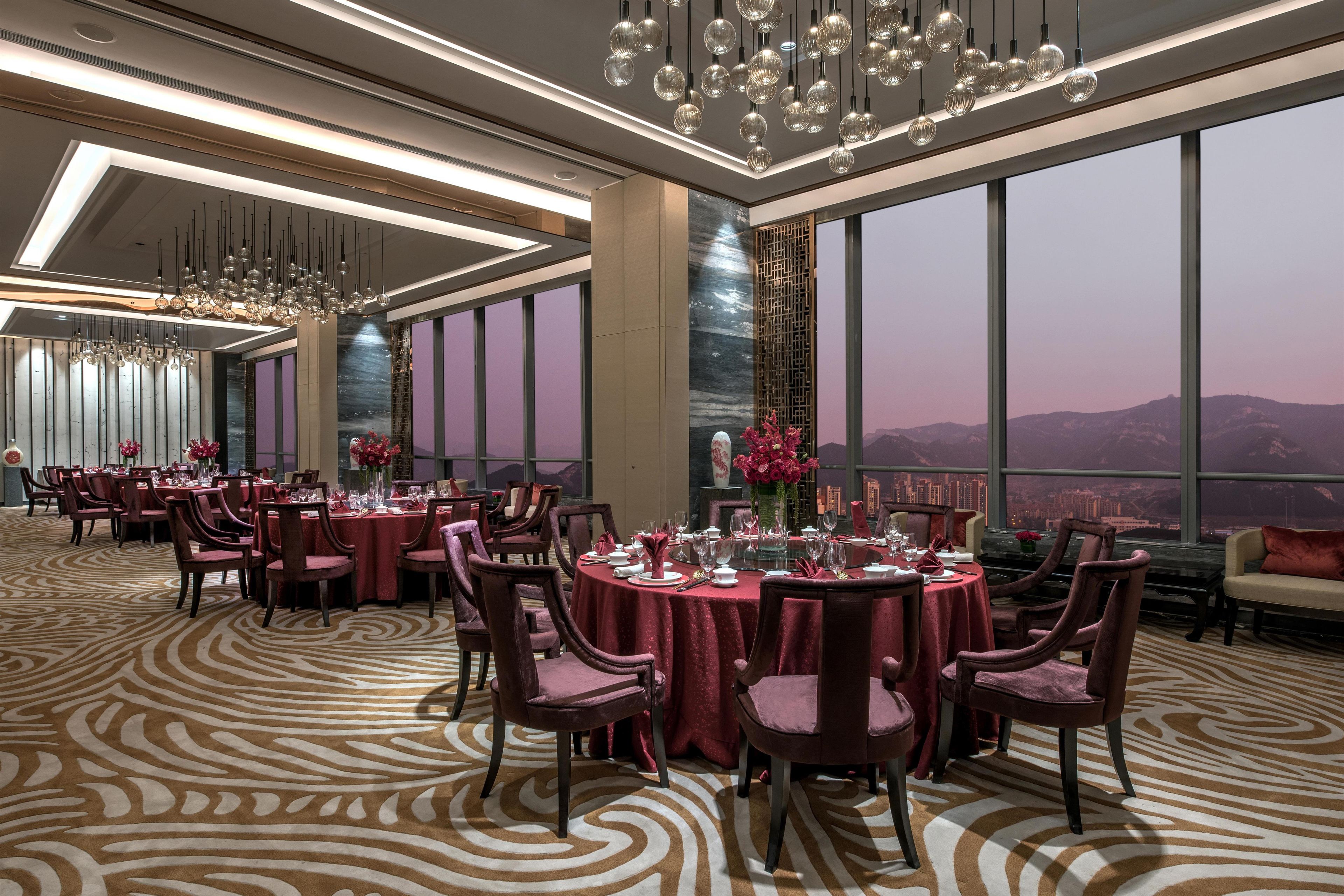Un restaurante de lujo con mesas redondas, manteles rojos y candelabros modernos.