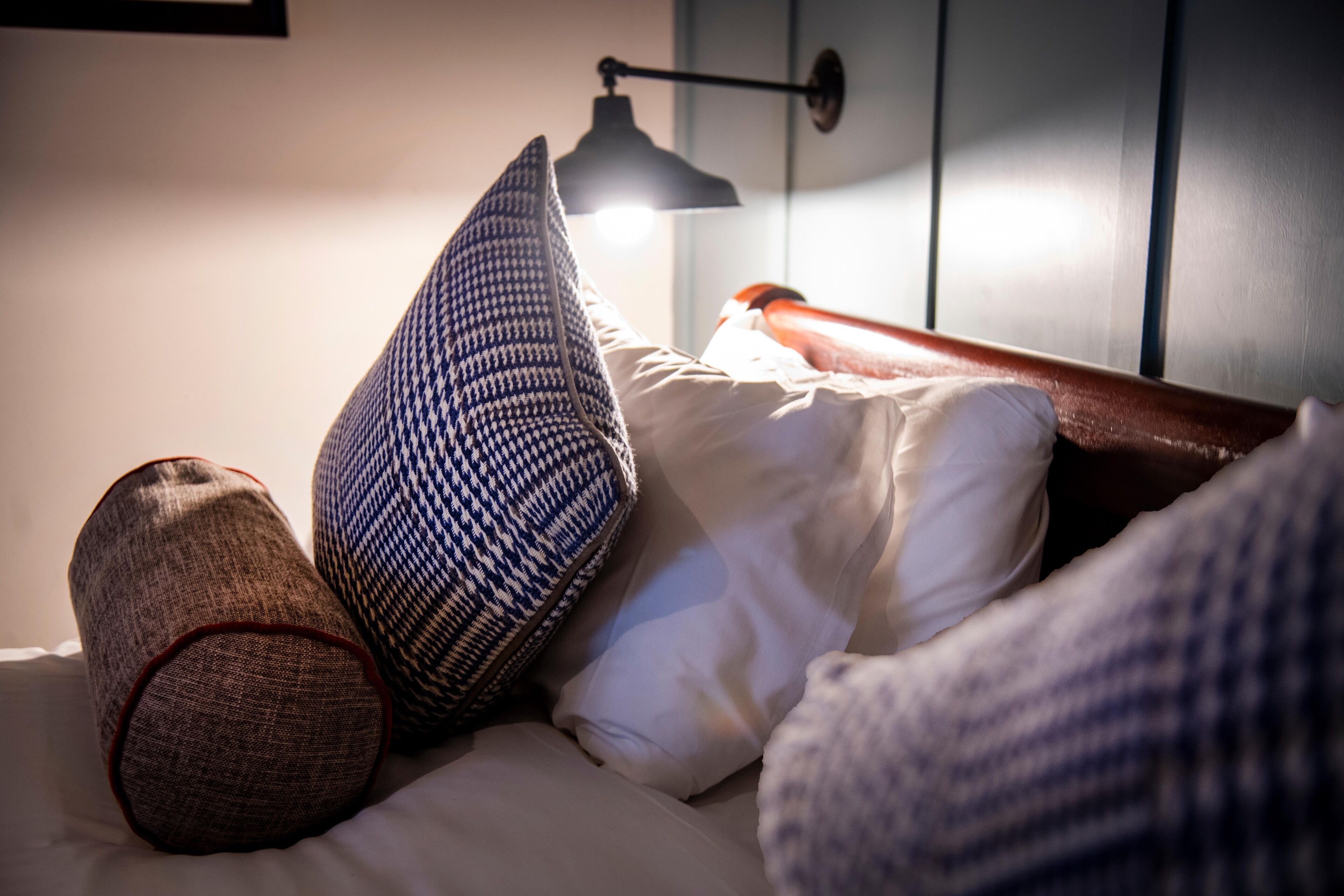 A bed with multiple pillows and a bedside lamp.