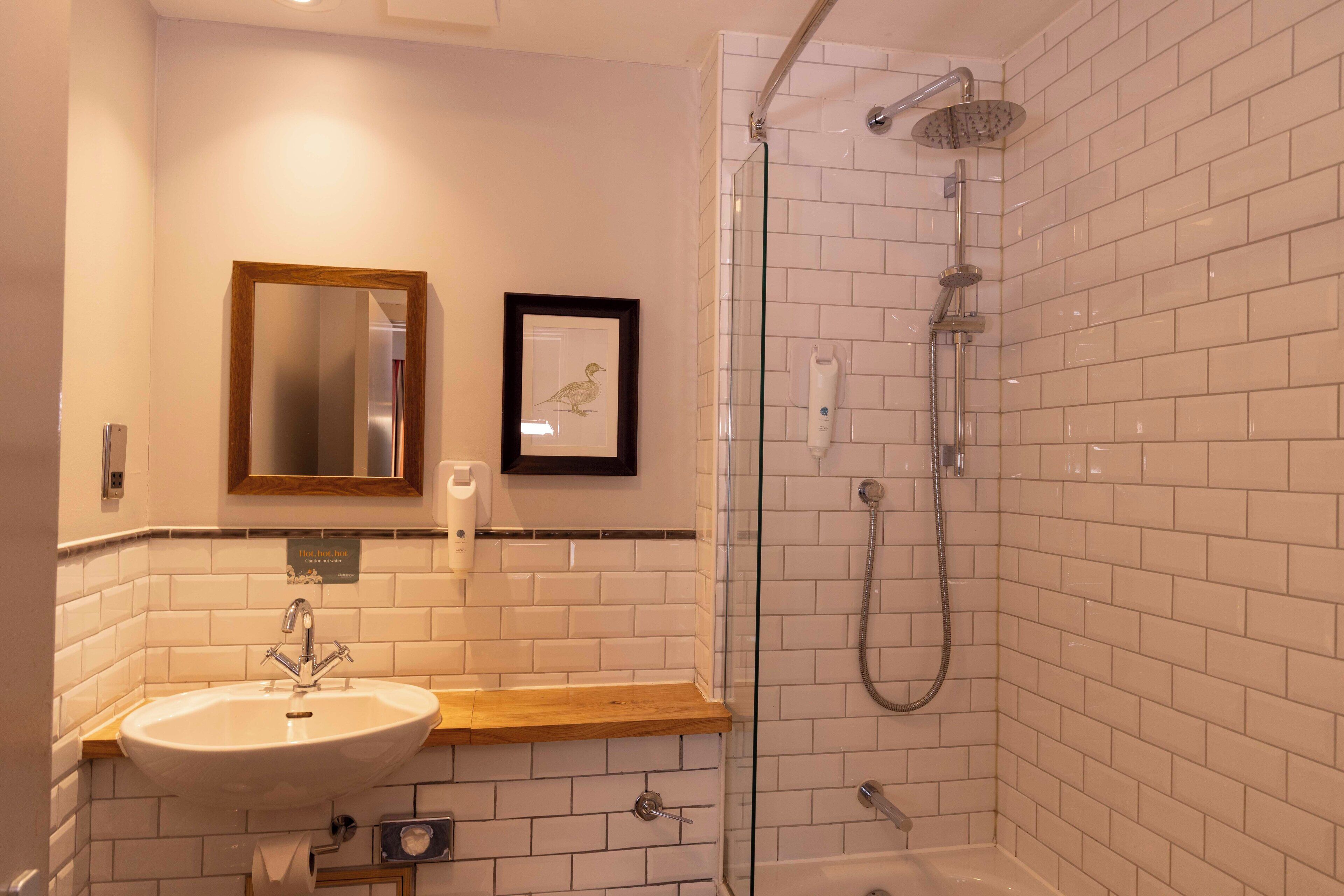 Ein Badezimmer mit Waschbecken, Spiegel, einem gerahmten Bild und einer Duschkabine.