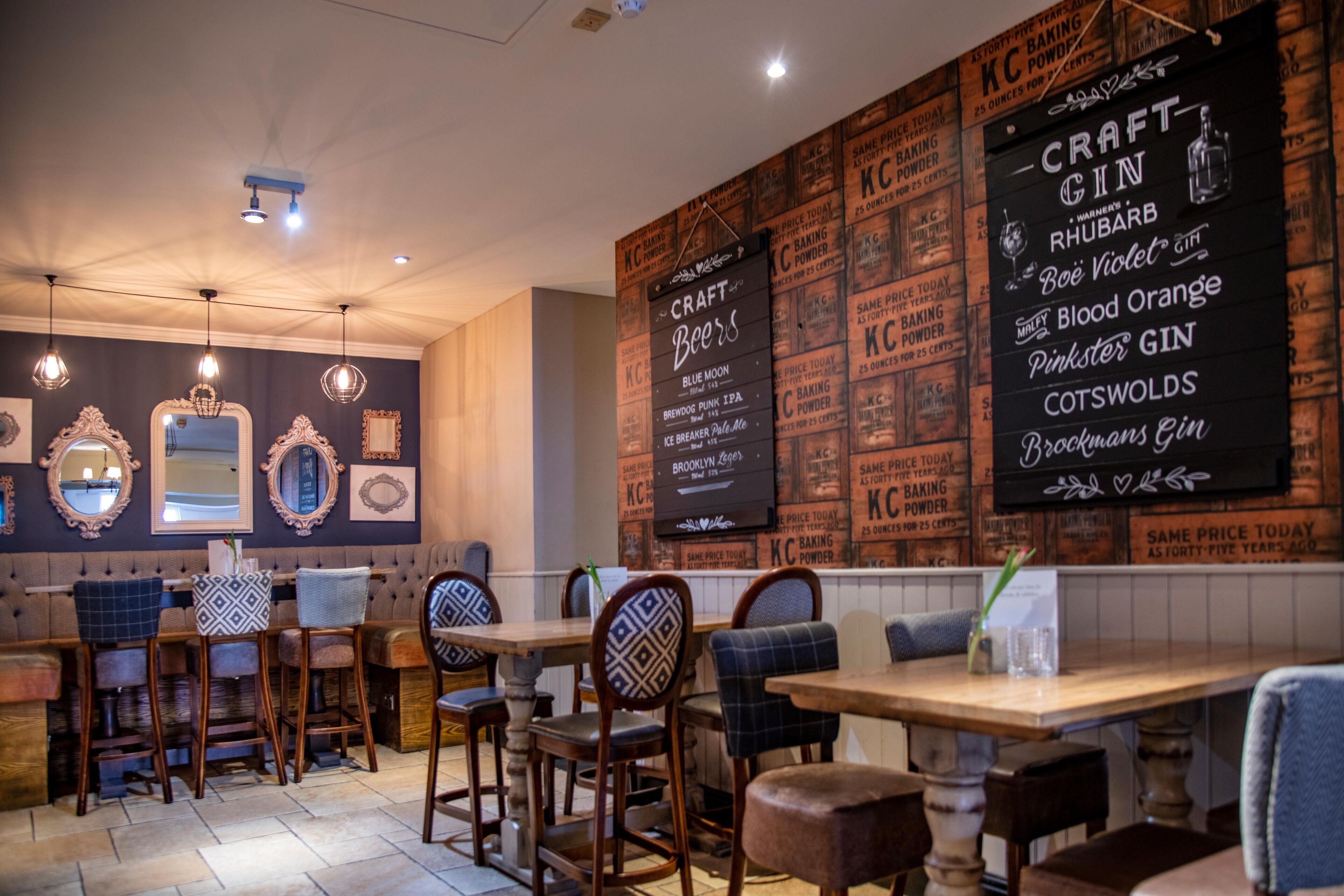 L’intérieur d’un restaurant est agrémenté de tables et de chaises en bois, d’un menu affiché au mur présentant une sélection de bières artisanales et d’une décoration de style vintage.