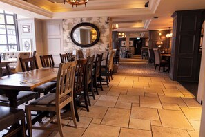 A spacious dining area with a long wooden table and multiple chairs, a large mirror on the wall, and a patterned carpet. - Greswolde Arms Hotel by Chef and Brewer Collection (Solihull)