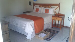 A bedroom with a bed, nightstands, a wicker basket, and a striped rug.