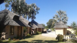 A resort with thatched-roof cottages, palm trees, and a clear sky.