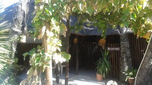 A reception area with a sign, a thatched roof, and potted plants.