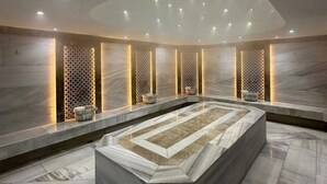 Moderni spa-alue, jossa on suuri, lämmitetty allas, marmoriseinät ja upotetut valaisimet.