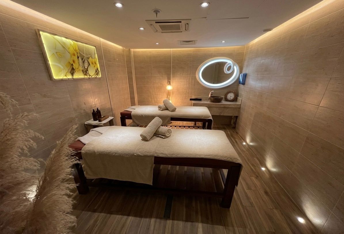 A spa room with two massage tables, a wall-mounted mirror, and a decorative light fixture.