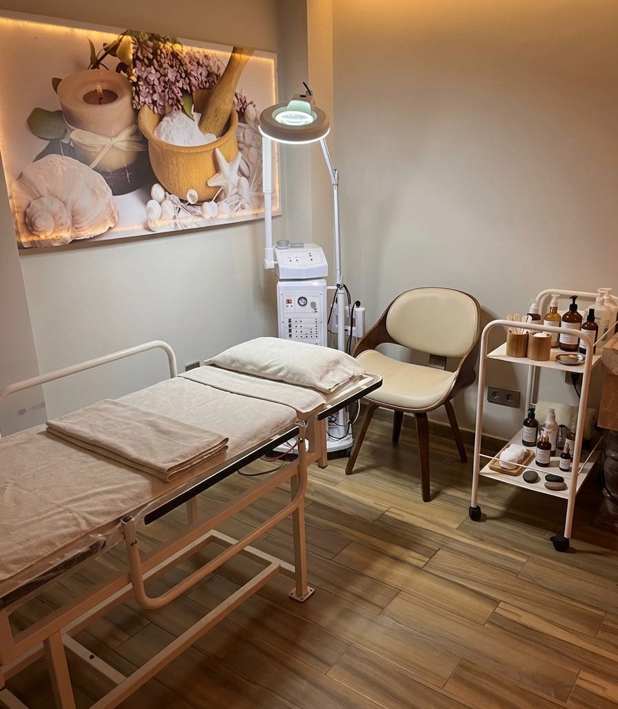 A medical examination room with a bed, examination table, chair, and medical equipment.