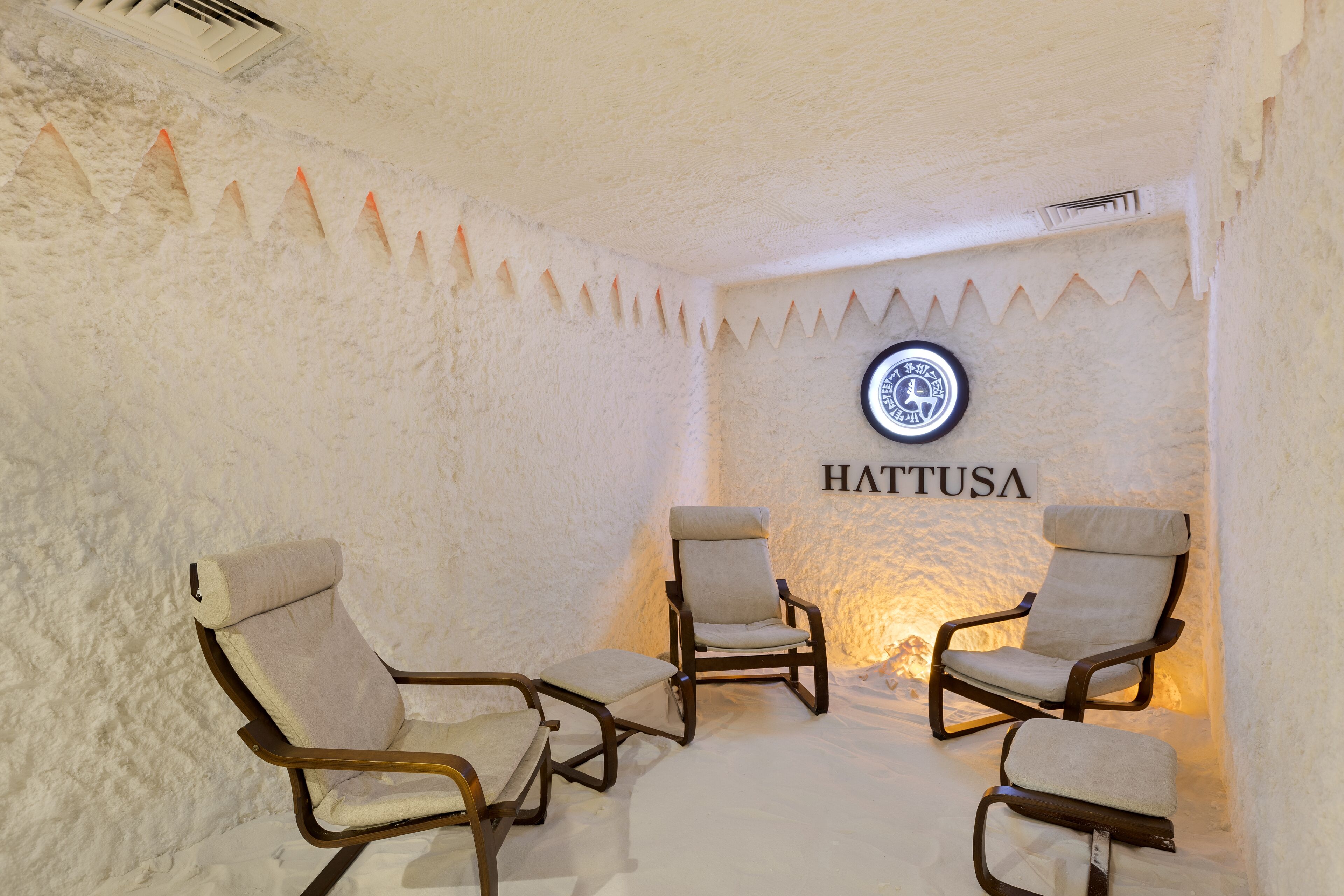Una habitación con tres sillas y una pared con la palabra "HATTUSA".