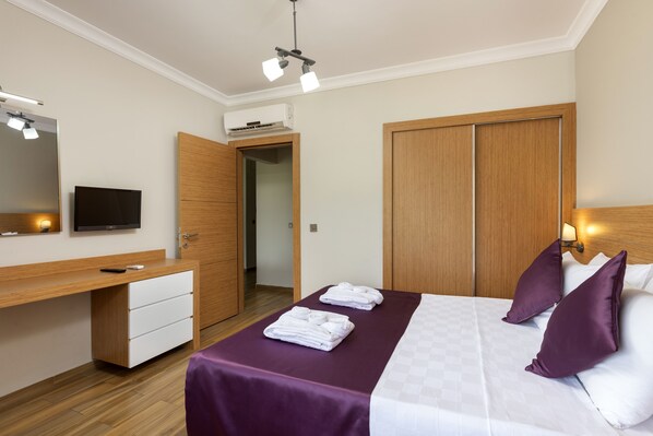 Habitación de hotel con cama, escritorio, televisión y armario.
