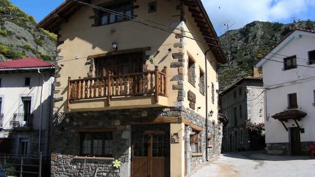 Un bâtiment en pierre de deux étages, doté d’un balcon, d’une porte en bois et d’un mur en pierre.