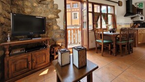 Un salon chaleureux avec un mur en pierre, un téléviseur, des meubles en bois et une vue sur l’extérieur.