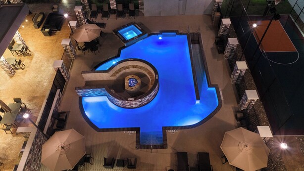 An outdoor swimming pool with a circular hot tub, surrounded by lounge chairs and umbrellas. - Residence Inn by Marriott Houston West/Beltway 8 at Clay Rd. (Houston)