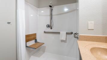 A shower with a handheld showerhead, a towel rack, and a wooden shelf.