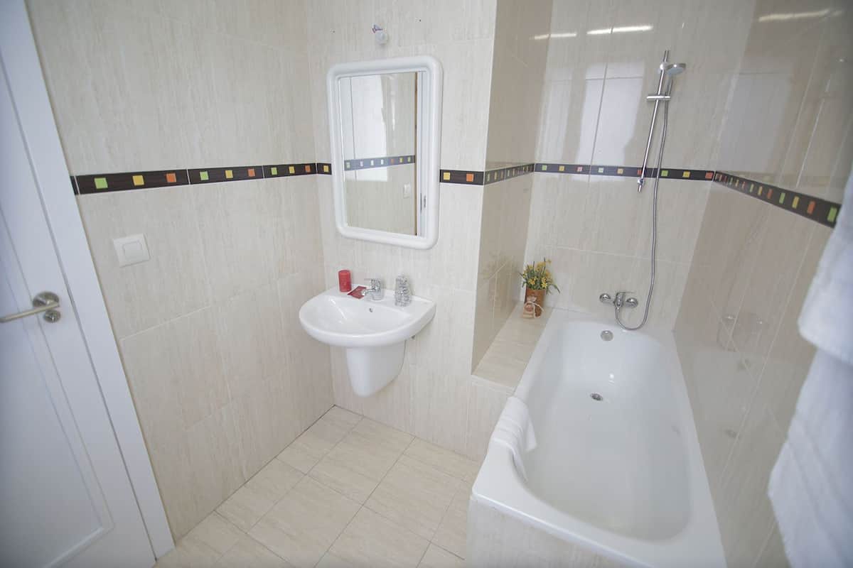 Un baño con lavamanos, espejo y bañera.