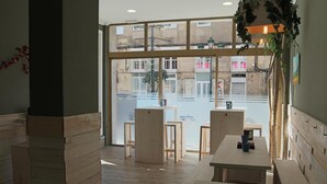 A modern interior with wooden furniture, large windows, and a view of the street. - Alda Estación Vigo (Vigo)