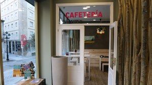 A cafe interior with a wooden table, a large planter, and a menu board. - Alda Estación Vigo (Vigo)