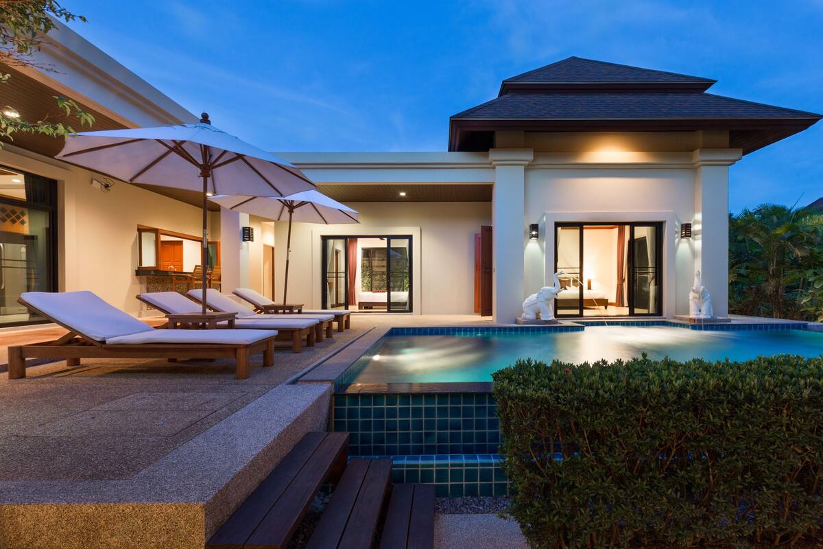 Une maison moderne dotée d’une piscine, de chaises longues et de parasols.