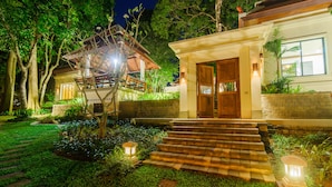 A well-lit residential property with a wooden staircase leading to a front door, surrounded by lush greenery and a stone pathway. - Nai Harn Baan-Bua Villas (Rawai)