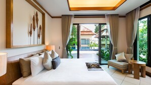 A hotel room with a large bed, a sofa, a small table, and a view of the outside. - Nai Harn Baan-Bua Villas (Rawai)