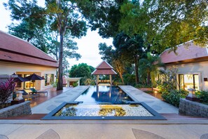 Un resort moderno con piscina central, zona de descanso y dos villas para huéspedes.