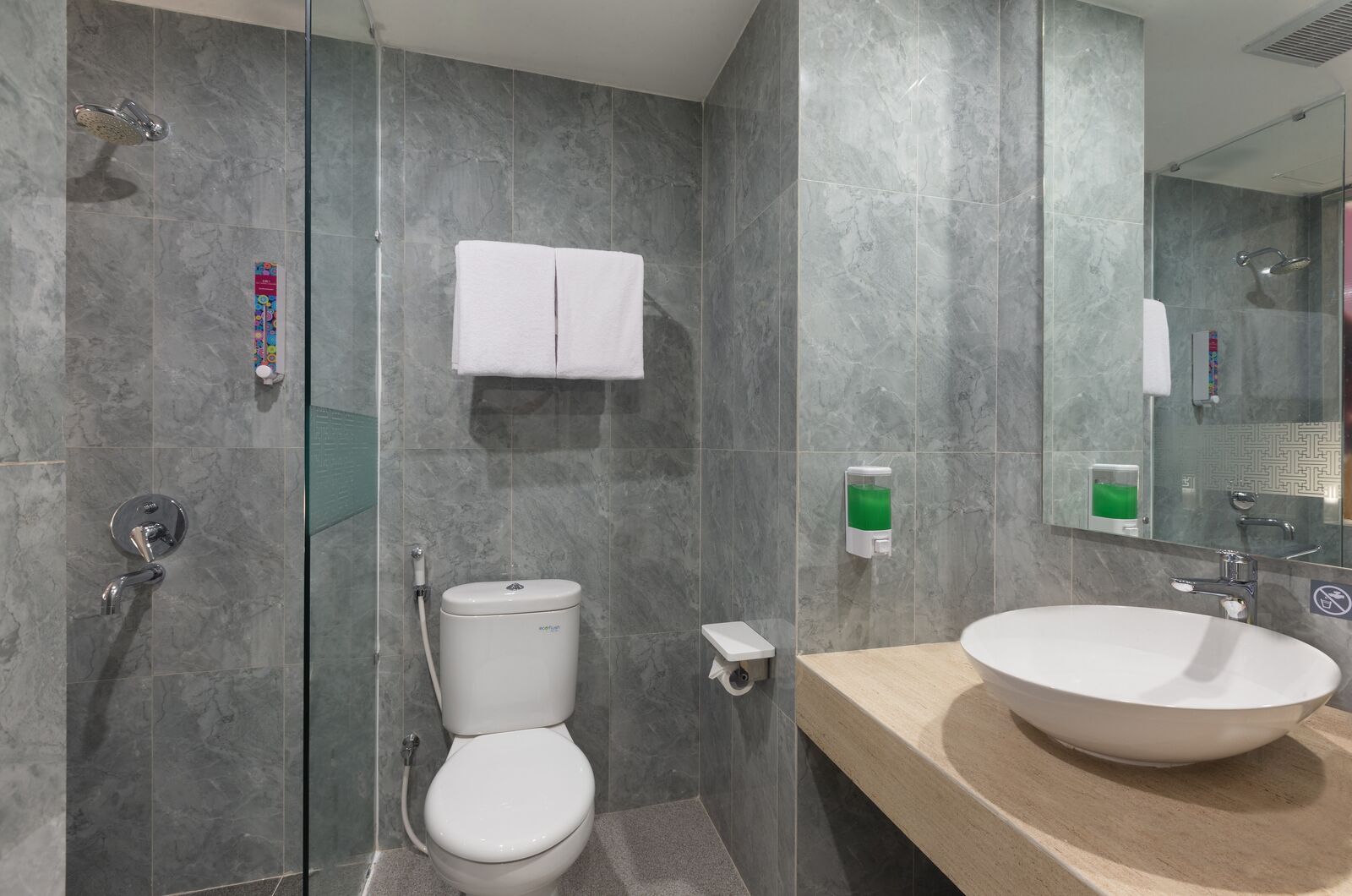 A modern bathroom with a glass-enclosed shower, a toilet, a sink with a beige countertop, and a mirror.