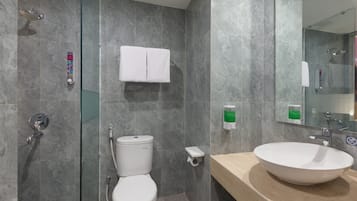 A modern bathroom with a glass-enclosed shower, a toilet, a sink with a beige countertop, and a mirror.