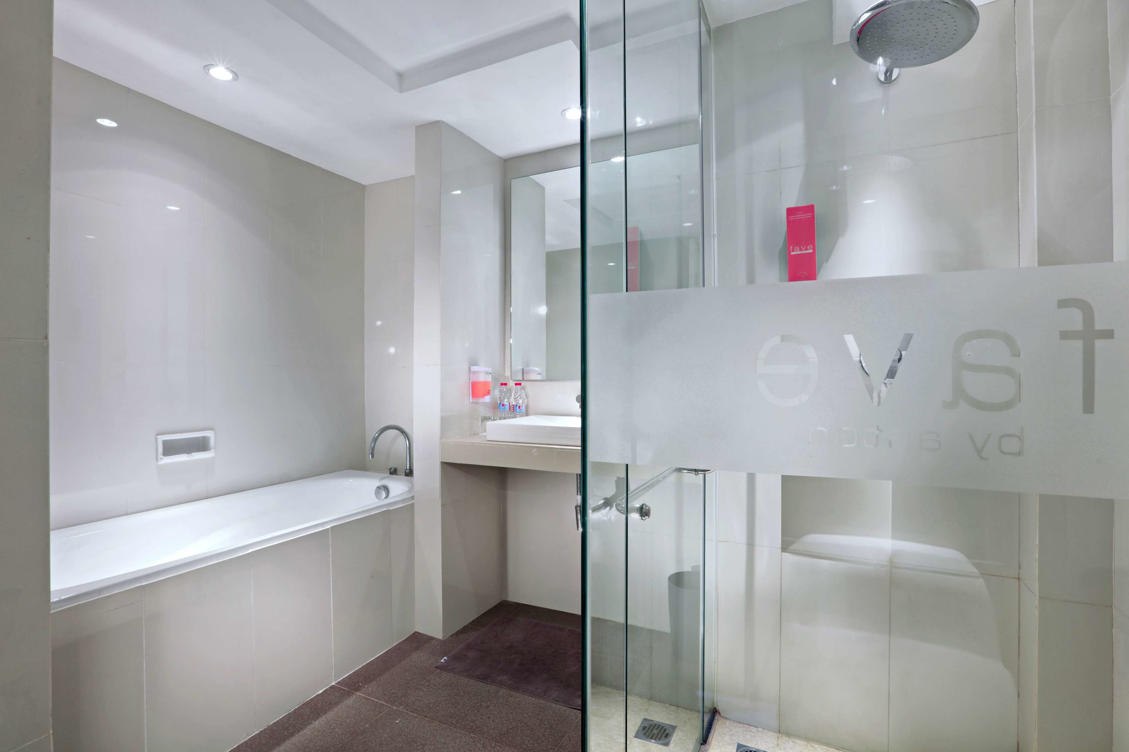 Een moderne badkamer met een douchecabine van glas, een witte wastafel en een bad.