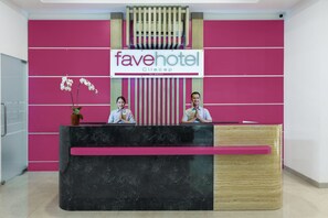 A reception desk at Fave Hotel with a modern design, featuring a black marble top and a wooden accent. - favehotel Cilacap (Cilacap)