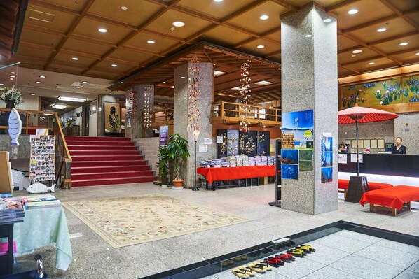 Un hall d’entrée avec un escalier, un comptoir de réception et un présentoir à magazines.