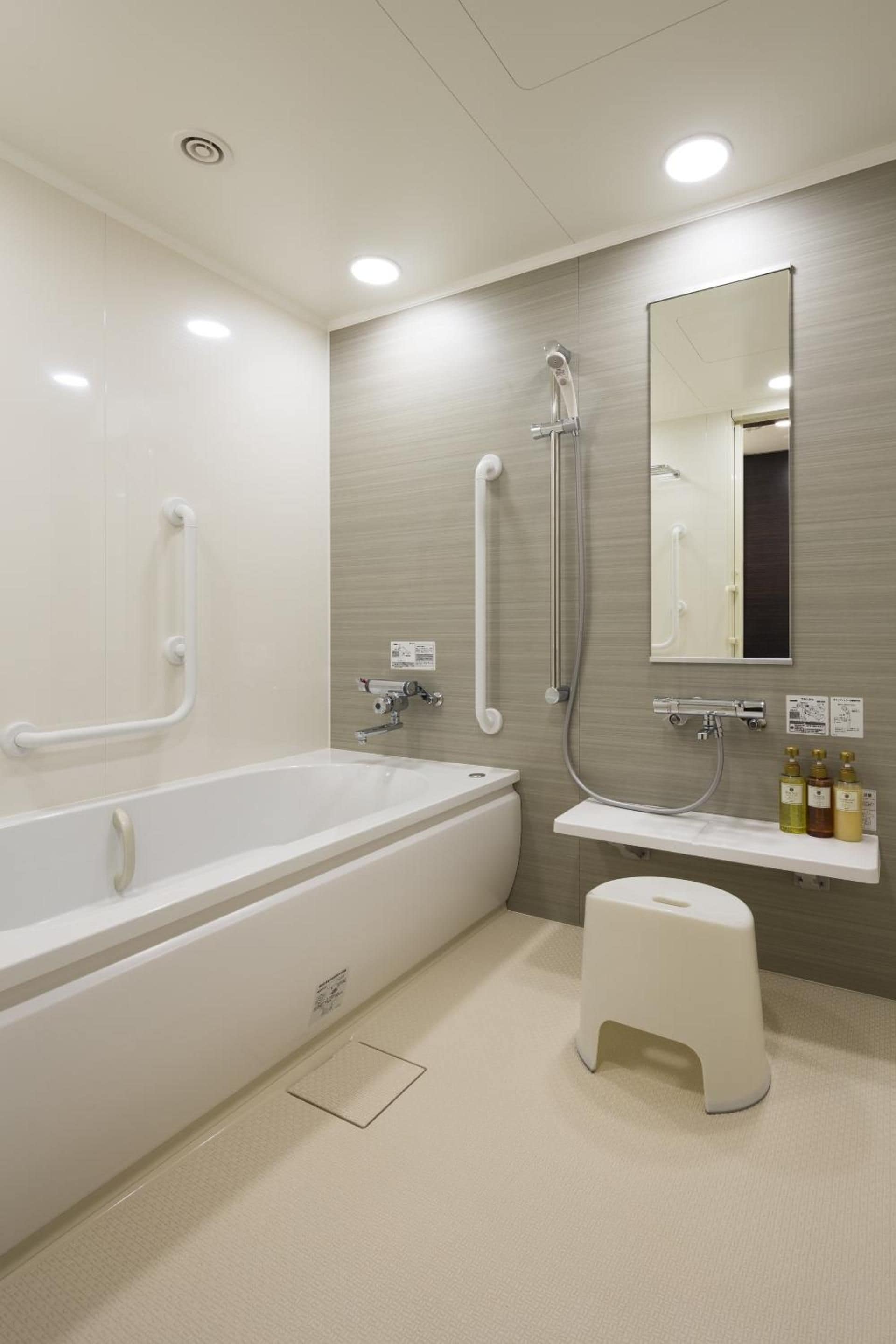 Een moderne badkamer met een ruim bad, een douche, een wastafel en een spiegel.