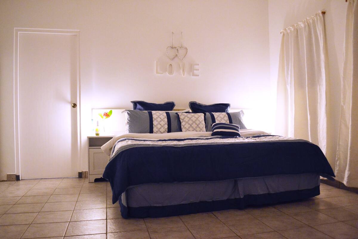 A bedroom with a bed, a nightstand, and a wall decoration.