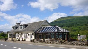 A restaurant with a traditional design, featuring a stone facade, large windows, and a glass extension. - The Golden Larches Cafe and B&B (Lochearnhead)