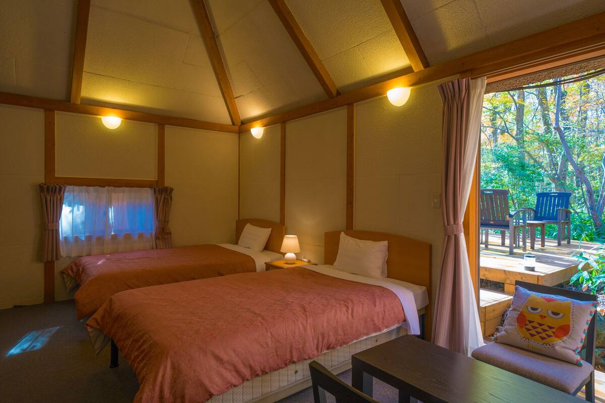 A room with two beds, a table, and a chair.