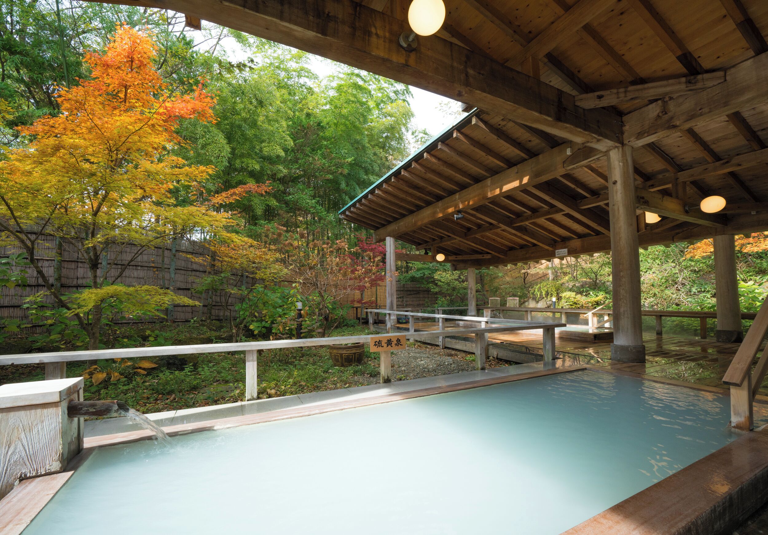 Un onsen japonès tradicional amb terrassa de fusta i zona coberta.