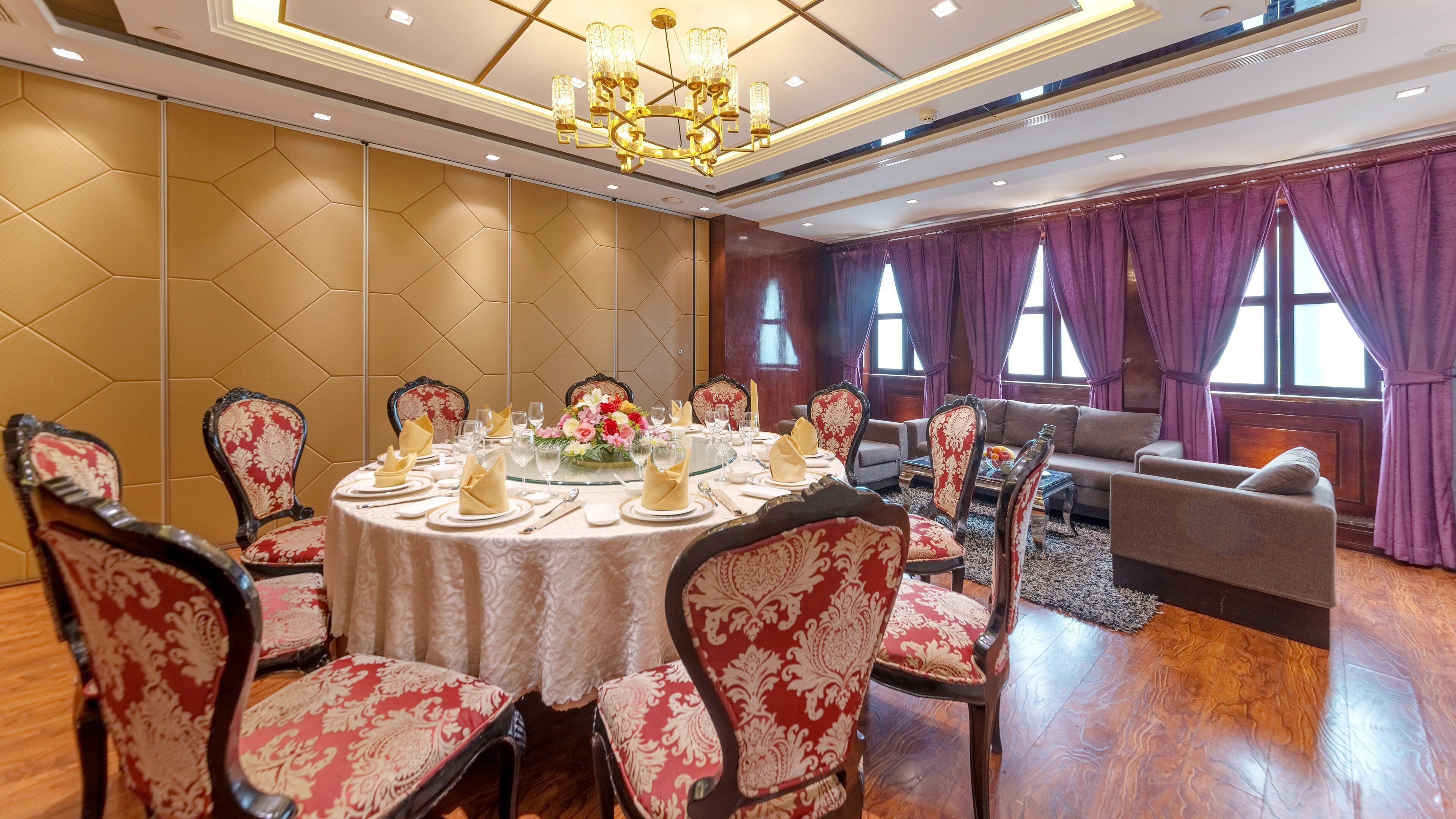A formal dining room with a round table set for a meal, surrounded by ornate chairs.