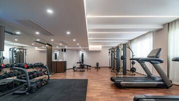 A modern gym with exercise equipment, a treadmill, and a mirrored wall.
