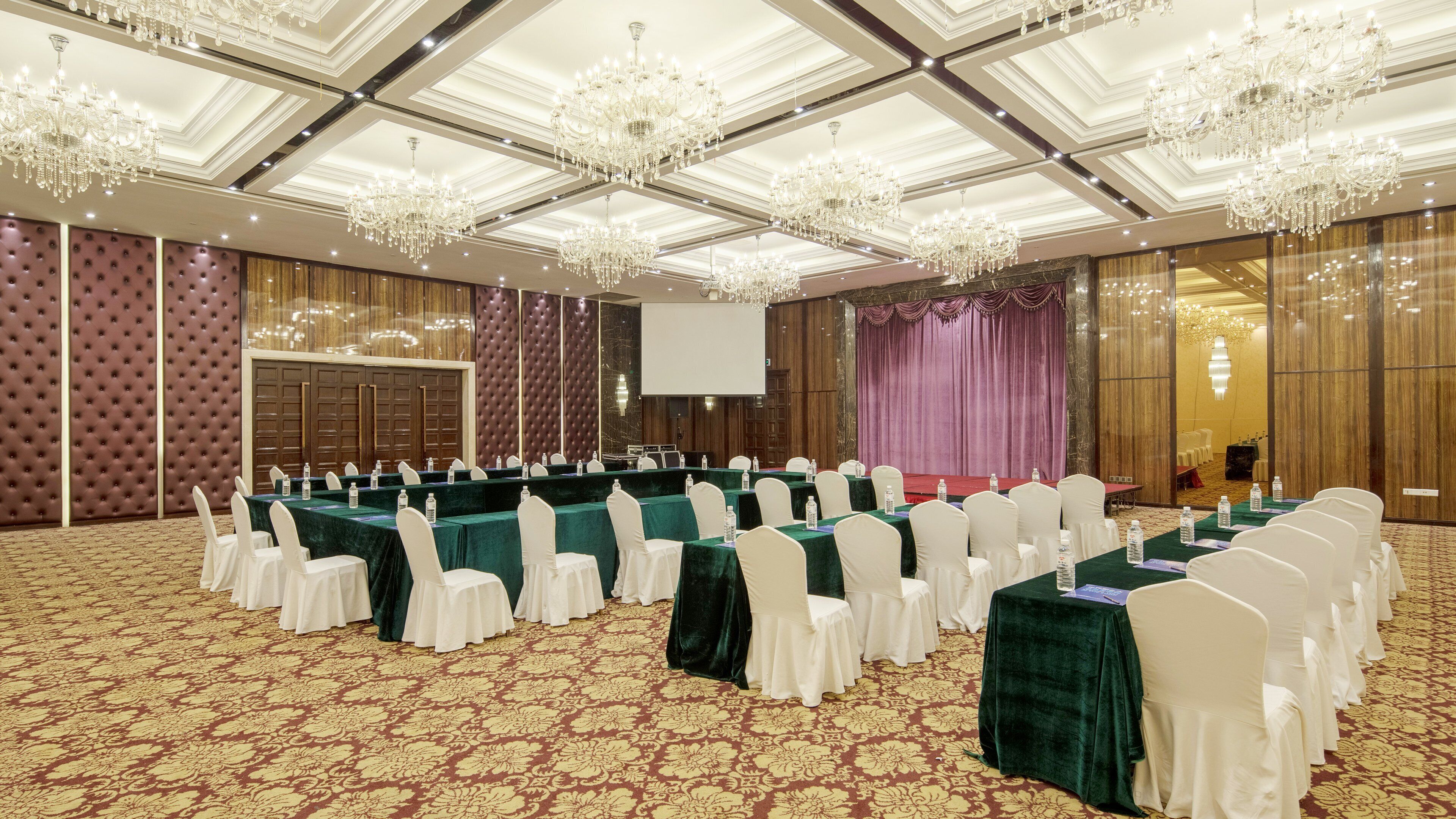 A conference room with a long table, white chairs, and a large screen.