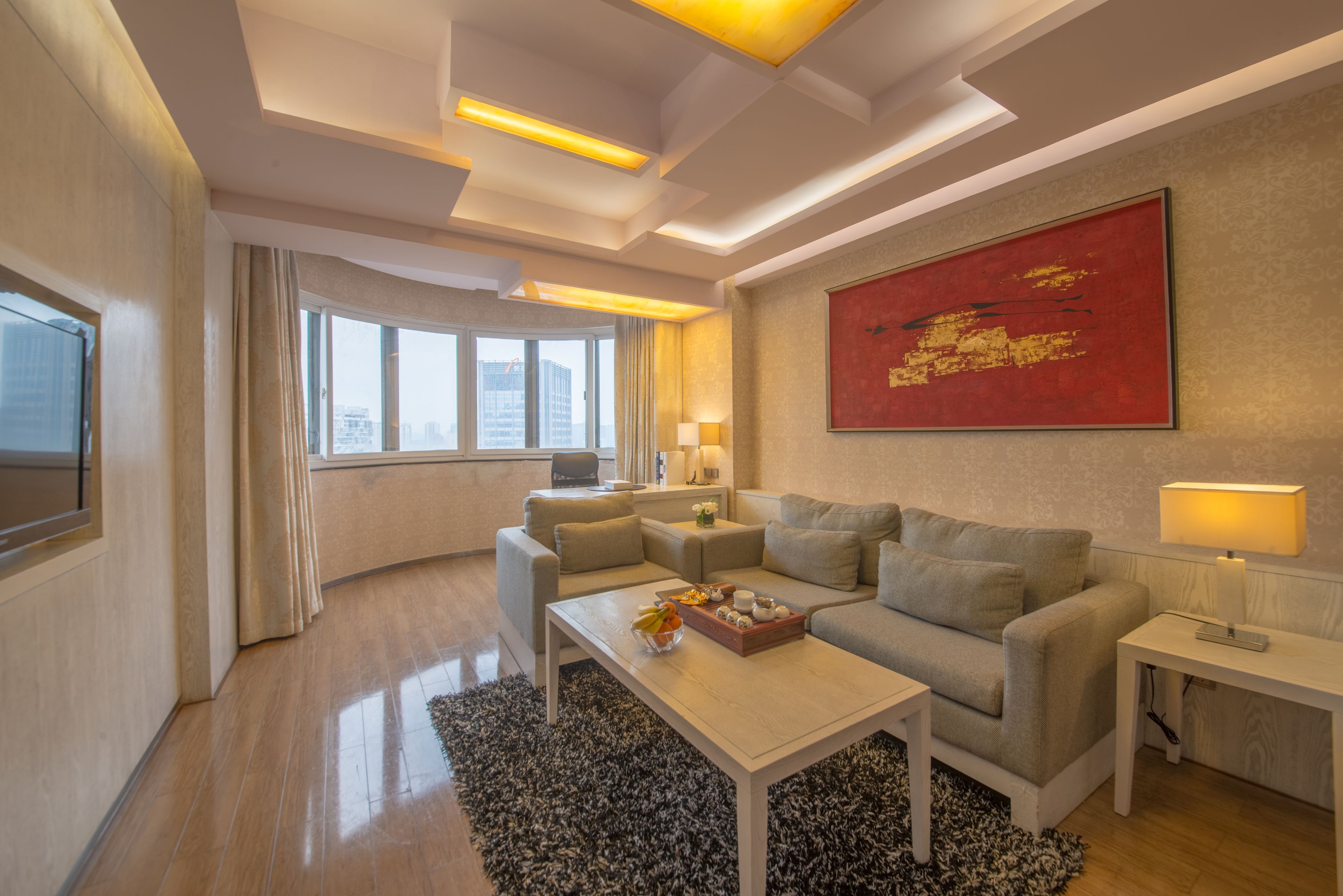 A modern living room with a sofa, coffee table, and a large painting on the wall.