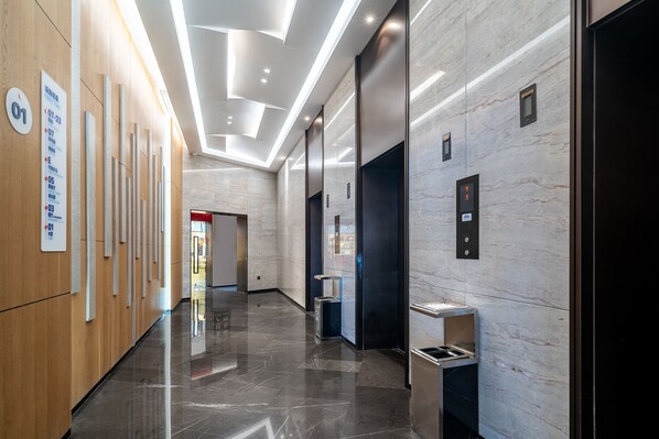A modern hallway with a polished marble floor, wooden paneling, and a series of numbered signs on the left. - Holiday Inn Express Xiamen Lushan by IHG (Xiamen)